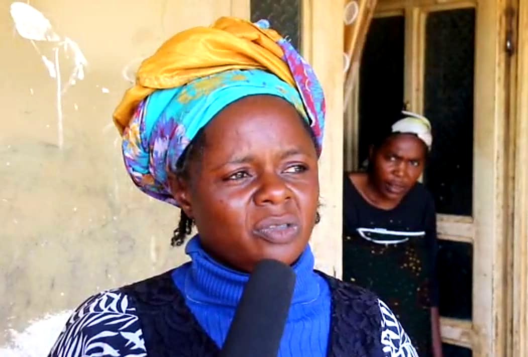 Rahila Bibi, in a headwrap, speaking to a reporter outside her home in Angwan Tsapta